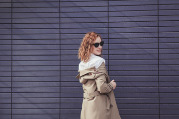 Stylish happy young woman wearing trendy coat and sunglasses