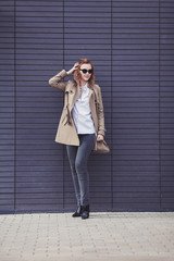 fashion woman in coat posing near wall outdoor