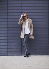 elegant beautiful woman in coat posing near wall, fashion trend