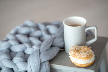 Soft fluffy plaid in the interior with flowers chair and cup of coffee.