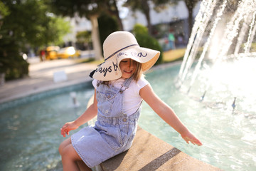 Caucasian child girl in hat, fountain in Turkey