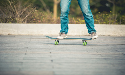 Fototapeta na wymiar Skateboarder legs riding a skateboard at park