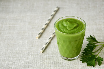 Glass of green vegetable smoothie on a gray background