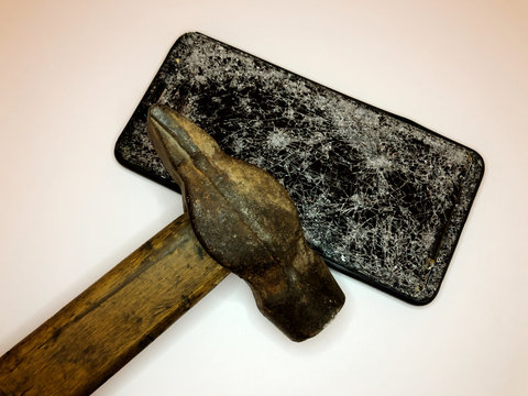 Broken glass mobile phone on a white background. Hammer beating on the phone.