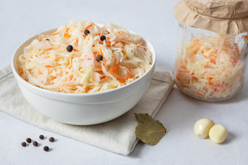 Homemade sauerkraut. Fermented food. Sauerkraut with carrots in a white bowl on a white background close up.