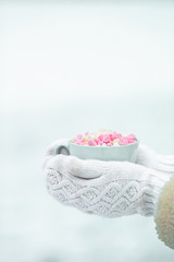 Female hands holdink white cup of coffee with white and pink marshmallows