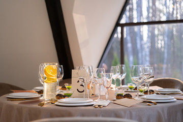 Chic and elegant, gold-plated cutlery and white plates, table setting with empty plates. On the table is an orange lemonade.
