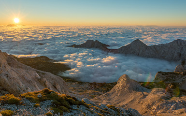 Spectacular morning mountain panorama with sun raising above sea of clouds.