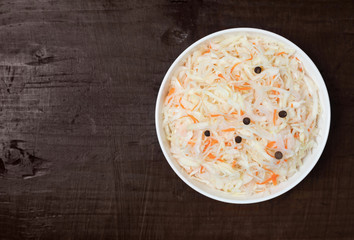 Homemade sauerkraut. Fermented food. Sauerkraut with carrots in a bowl on a dark wooden background.