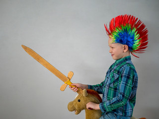 happy boy in plaid shirt is rolling on rocking horse toy. baby with wonderful punk-style colored...