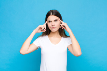 young pretty woman looking concentrated and thinking hard on an idea, imagining a solution to a...