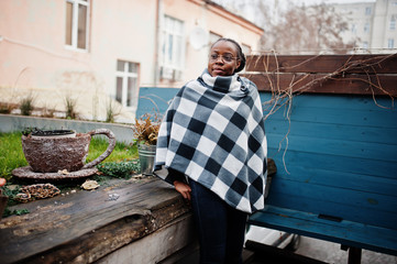 African woman in checkered cape posed outdoor.