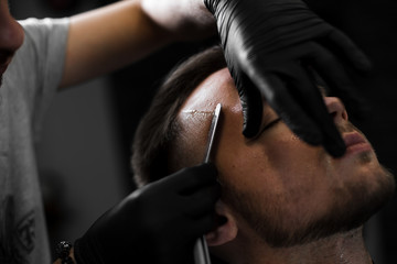 A man shaves his forehead and temples with a razor.