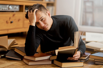Young handsome student learns on the floor with books for exam 