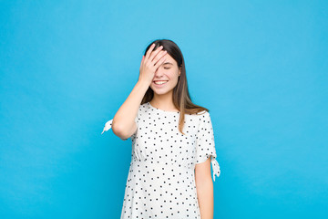 young pretty woman laughing and slapping forehead like saying d‚Äôoh! I forgot or that was a...