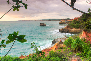 potrait mode for beauty of the high seas with blue and green beach water, unspoiled trees and high coral cliffs with very high waves in the Indonesian Indian Ocean