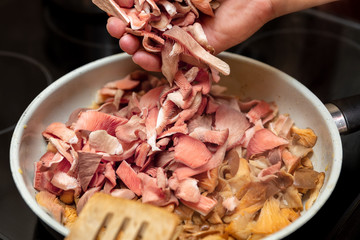 fresh pink oyster mushrooms roasting in a kitchen pan, gourmet food