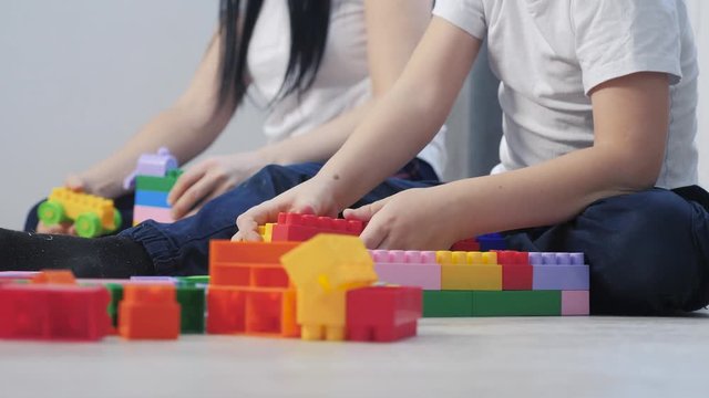 childhood happy family mom and children are playing concept little girl and boy brother and sister collects lifestyle constructor teamwork. child plays toys sitting floor. children play in team toys