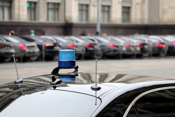 Blue flashing light and communication antennas on a government car on a city street. Concept of...