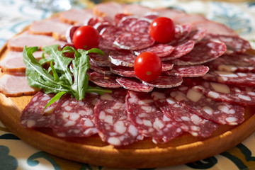 Slicing smoked sausage with cherry tomatoes on a wooden board