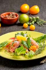 Cold salmon salad with green leaves, cucumber, avocado, lime and tomato on black stone background. Top view with copy space. Rustic style.