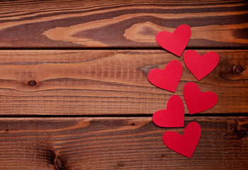 Red paper hearts on a dark wooden background. Valentine's Day