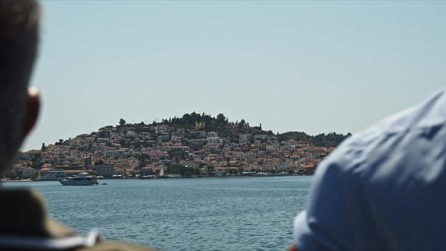 Navegando por la costa griega, frente a la isla de poros con el mar azul y bonitas casas a la distancia