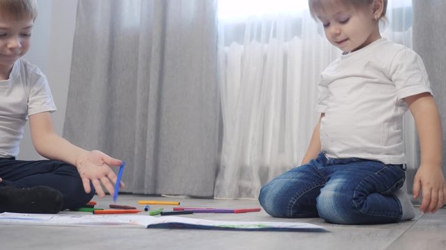 children draw with felt-tip pens in an album. little boy and girl concept childhood brother and sister lifestyle play paint on floor with colored markers