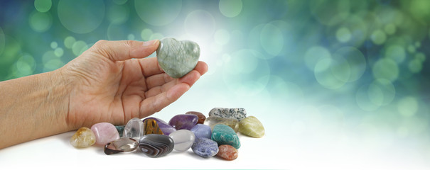 Crystal healer holding green puff heart stone - female hand offering a heart shaped crystal with a...