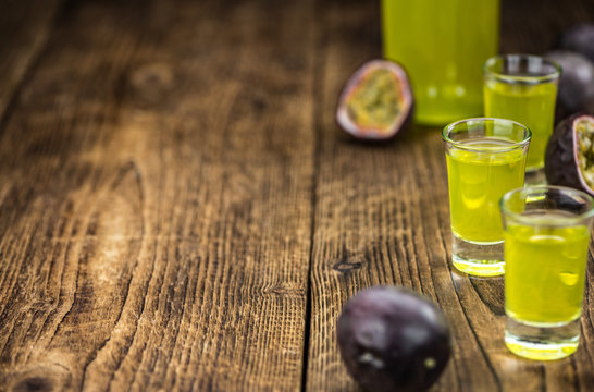 Some fresh Passion Fruit Liqueur on wooden background (selective focus; close-up shot)