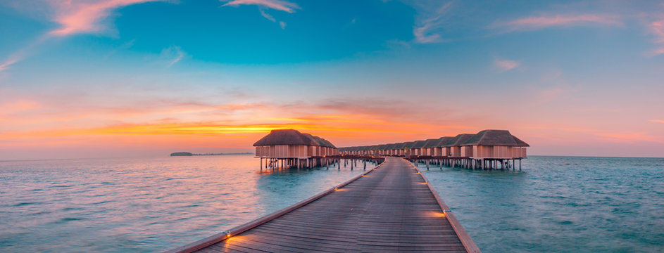 Maldives island sunset. Water bungalows resort at islands beach. Indian Ocean, Maldives. Beautiful sunset landscape, luxury resort and colorful sky. Artistic beach sunset under wonderful sky