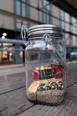 Train in glass jar on golden sand on a wooden desk with blurry background. Decoration in restaurant