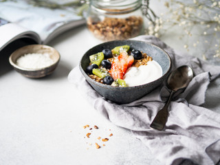 Delicious breakfast - granola with yogurt and berries and open magazine on the table. Copy space.