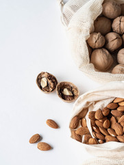 Reusable eco-friendly fabric bags for storage or shopping with various nuts on a white background. Copy space