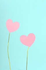 Fototapeta na wymiar Two sweet pink paper hearts on the colored gold wire against blue background. Concept of couple in love