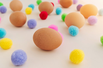 Easter eggs pattern with colorful pompons on beige background.