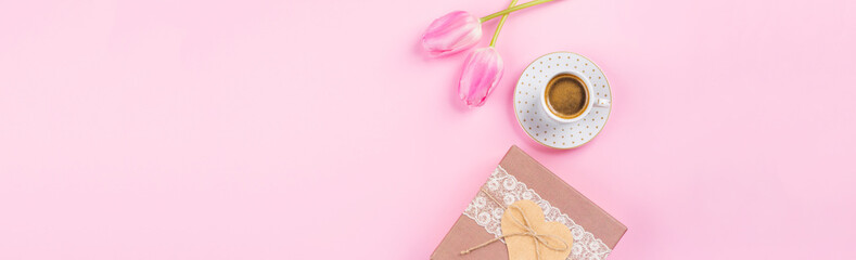 Cup of coffee and tulips, gift box with heart on millennial pink background. Concept banner for mothers day, valentines day, good morning flat lay