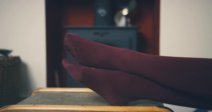Woman resting her feet by the fireplace in living room