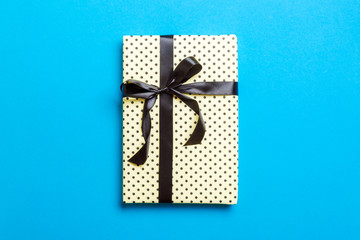 wrapped Christmas or other holiday handmade present in paper with black ribbon on blue background....