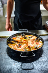 Spanish cuisine, man making paella, famous dish with rice and seafood from Valencia