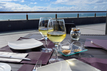 Obraz premium Table served for dinner on outside terrace with glasses of cold white wine and sea view