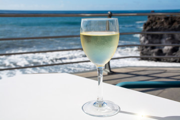 Summer holiday on sea, drinking white wine on outdoor terrace with sea view in sunny day