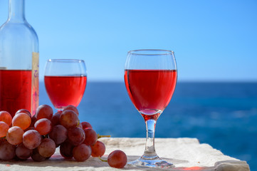 Two glasses of rose wine served outdoor with pink grapes fruits on tropical island La Palma, Canary islands, Spain with beautiful blue ocean view