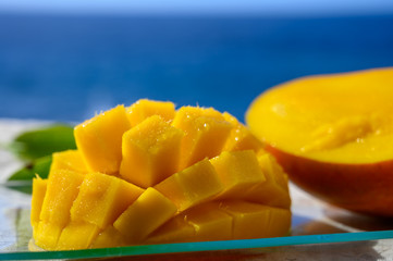 Fresh ripe sweet yellow mango fruit served on glass plate with blue seaview background