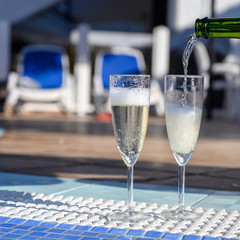Pool party with two glasses with  bubbles white champagne or cava wine, romantic event or all inclusive holidays