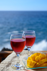 Two glasses with rose wine served outdoor with exotic fruits on tropical island La Palma, Canary islands, Spain with beautiful blue ocean view