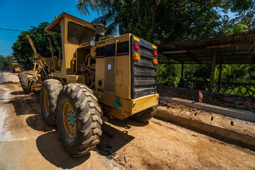 Fototapeta na wymiar Grader is working on road construction. Grader industrial machine on construction of new roads. Heavy duty machinery working on highway. Construction equipment. Compaction of the road.