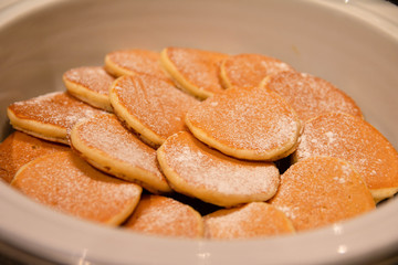 Stacked of mini pancakes on a breakfast buffet.
