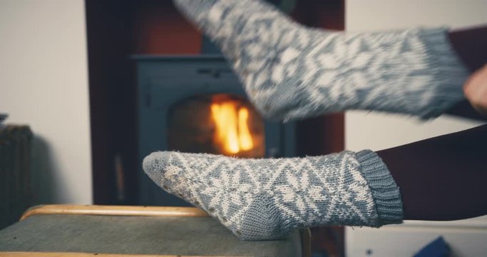 Young woman putting on heavy socks by the fireplace