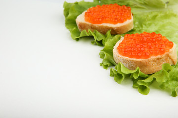 sandwiches with red caviar and lettuce on white background with copy space.